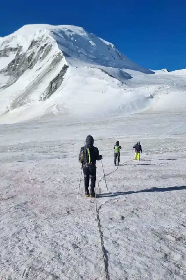 Mountaineers traverse the icy expanse of Altai Tavan Bogd, roped together for safety and teamwork